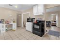 Practical kitchen with black appliances, tiled floor, adjoining room with desk, and cabinetry at 4108 Drexel Ave, Orlando, FL 32808