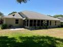 Backyard featuring a screened lanai, green grass, and mature shrubbery at 6419 Borg St, Leesburg, FL 34748