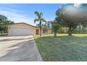 Single-story house with front lawn, mature trees, and a two-car garage in a nice neighborhood at 717 Wedge Ln, Kissimmee, FL 34759