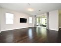 Spacious living room with dark wood floors, large windows, and sliding door access to the outdoors at 8742 Peachtree Park Ct, Windermere, FL 34786