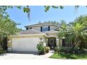 Charming two-story home featuring a well-maintained lawn, two car garage, and a welcoming entrance with a beautiful palm tree at 9573 Southern Garden Cir, Altamonte Springs, FL 32714