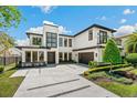 Beautifully landscaped modern home featuring a clean white facade, balcony, and stylish driveway at 1700 Palm Ave, Winter Park, FL 32789