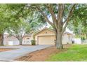Well-kept home featuring a wide driveway, mature trees, and pleasant landscaping at 225 Loma Del Sol Dr, Davenport, FL 33896