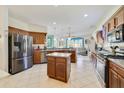 Spacious kitchen featuring stainless steel appliances, center island, tile flooring, and wood cabinets at 26712 Augusta Springs Cir, Leesburg, FL 34748
