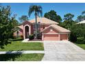 Two-story home boasting a tile roof, three-car garage, mature palm tree, and well-manicured landscaping at 3020 Zaharias Dr, Orlando, FL 32837