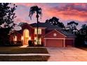 A beautiful house with a well-manicured lawn is silhouetted by a colorful sunset at 3020 Zaharias Dr, Orlando, FL 32837