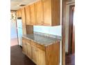 Kitchen with wooden cabinets and stone countertops, with a refrigerator in the adjacent area at 311 E Bridgers Ave, Auburndale, FL 33823