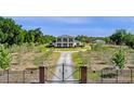View of a beautiful home with a circular driveway, surrounded by trees and greenery, captured behind an ornate metal gate at 4232 Spring Ln, Lakeland, FL 33811