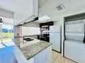 Well-lit kitchen with granite countertops, appliances and stackable washer and dryer at 658 Caribbean Dr, Davenport, FL 33897