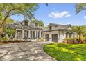 Beautiful home exterior with a three-car garage, a circular driveway, and lovely landscaping at 8440 Woburn Ct, Windermere, FL 34786