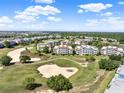 Sprawling golf course community with manicured greens, sand traps, and various condo buildings under a bright sky at 1112 Sunset View Cir # 302, Reunion, FL 34747