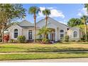 Charming single-story home featuring mature palm trees, arched windows, and a well-manicured lawn at 11401 Willow Stowe Ln, Windermere, FL 34786