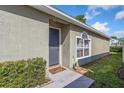 Inviting front entry with a gray door, manicured bushes, and a tiled entryway at 12817 Parkbury Dr, Orlando, FL 32828