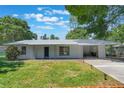 Charming single-story home featuring a metal roof, covered porch, and well-maintained front lawn with mature trees at 219 Stribling Dr, Auburndale, FL 33823