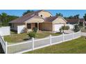 This home features an attached two-car garage, neutral paint, and an manicured front yard with a white picket fence at 602 Milan Dr, Kissimmee, FL 34758