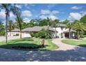 Elegant white home with lush landscaping, a curved driveway, and swaying palm trees on a sunny day at 980 Geryl Way, Deland, FL 32724
