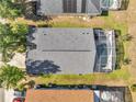 Aerial view of the backyard with a screened in pool and some patio furniture surrounded by grass and nearby trees at 166 Laurel Ridge Pass, Davenport, FL 33897