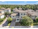 Townhome with a tile roof and brick driveway situated in a community surrounded by trees at 1339 Shinnecock Hills Dr, Davenport, FL 33896