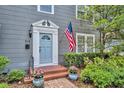Close-up of the entry with an American flag, brick steps, potted plants, and decorative trim around the light blue door at 216 E Vanderbilt St, Orlando, FL 32804