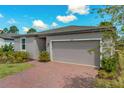 Single-story home featuring a brick driveway, attached garage, and manicured landscaping at 439 Sarah Nicole Way, New Smyrna Beach, FL 32168