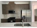 Modern kitchen featuring stainless steel appliances, gray backsplash, and quartz countertops at 6712 Golden Eagle Blvd, Howey In The Hills, FL 34737