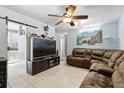 Inviting living room featuring tile floors, ceiling fan and a comfortable oversized brown sectional couch at 7727 Arezzo Ave, Orlando, FL 32819