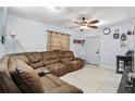 Inviting living room featuring tile floors, ceiling fan and a comfortable oversized brown sectional couch at 7727 Arezzo Ave, Orlando, FL 32819