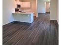 Modern kitchen featuring white cabinets, an island, and stylish wood-look flooring throughout the open-concept living space at 976 Commons Way, Port Orange, FL 32129