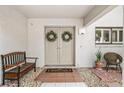 Close-up of condo entrance with double doors, welcome mat, bench, and charming decorative details at 1000 Winderley Pl # 140, Maitland, FL 32751