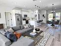 Open-concept living area with modern decor, featuring a spacious gray sofa and a stylish kitchen with stainless steel appliances at 2406 Sw 163Rd Pl, Ocala, FL 34473