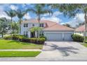 Charming two-story home boasts a three-car garage, lush landscaping, and a classic tile roof at 1786 Lee Janzen Dr, Kissimmee, FL 34744