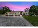 Beautiful home exterior at dusk, featuring a brick driveway and manicured landscaping at 32510 Wolf Branch Ln, Sorrento, FL 32776