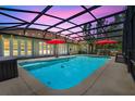 Sparkling pool with a screened enclosure, patio space for outdoor dining, and picturesque backyard views at twilight at 32510 Wolf Branch Ln, Sorrento, FL 32776