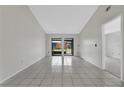 Spacious living room featuring bright white tile flooring and sliding glass doors to a screened patio at 66 Silver Falls Cir, Kissimmee, FL 34743