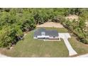 Aerial view of the charming white farmhouse on a large lot surrounded by mature trees and a long driveway at 6725 Sw 131St Cir, Ocala, FL 34481