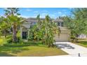 Two-story home exterior featuring a manicured lawn, palm trees, and a driveway leading to a two-car garage at 12636 Hammock Pointe Cir, Clermont, FL 34711
