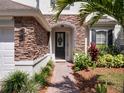 Close-up of the home's front door featuring stone accents, meticulous landscaping, and a brick walkway at 13156 Hatherton Cir, Orlando, FL 32832