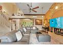 Comfortable living room with a stone fireplace, ceiling fan, neutral paint colors, and staircase at 14037 Fairway Willow Ln, Winter Garden, FL 34787