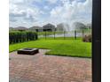 View of the lush backyard with grass, a brick patio, and a water feature at 16124 Azure Key St, Winter Garden, FL 34787