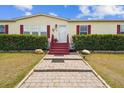 Charming home entrance with a brick walkway and bright red stairs at 18906 Merrich Rd, Orlando, FL 32820