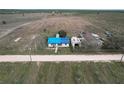Aerial view of a rural home with a blue roof, adjacent to a dirt road and expansive fields at 270 S Lake Patrick Rd, Frostproof, FL 33843