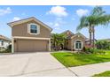 Inviting exterior featuring a two-story home with lush green lawn and meticulously landscaped front yard with palm trees at 2787 Cypress Head Trl, Oviedo, FL 32765