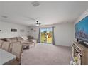 Bright living room featuring a comfortable sofa, ceiling fan, and sliding glass doors at 4743 Sw 114Th Pl, Ocala, FL 34476