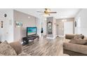 Cozy living room with wood-look floors, a ceiling fan, and a mounted television at 4801 Apple Blossom Ln, St Cloud, FL 34771
