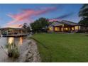 Picturesque waterfront backyard featuring a lush lawn leading to the water's edge and a covered boat dock at 616 Grand Cypress Pt, Sanford, FL 32771