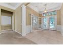 Spacious foyer with decorative glass doors, tiled floor, and elegant lighting fixture at 6550 Crestmont Glen Ln, Windermere, FL 34786