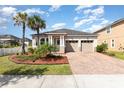 Inviting single-story home featuring a two-car garage, brick paver driveway, and lush landscaping at 8058 Corkfield Ave, Orlando, FL 32832