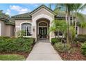 Inviting home entrance with double doors, decorative plants, manicured shrubs, and charming exterior lighting at 9138 Pinnacle Cir, Windermere, FL 34786