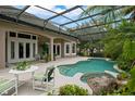 Secluded pool area with rock waterfall feature, screened enclosure, and lush tropical landscaping at 9138 Pinnacle Cir, Windermere, FL 34786