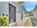 Close-up of a gray front door with a brick walkway, complementing the exterior of the house and surrounding landscaping at 1840 Shumard Ave, St Cloud, FL 34771